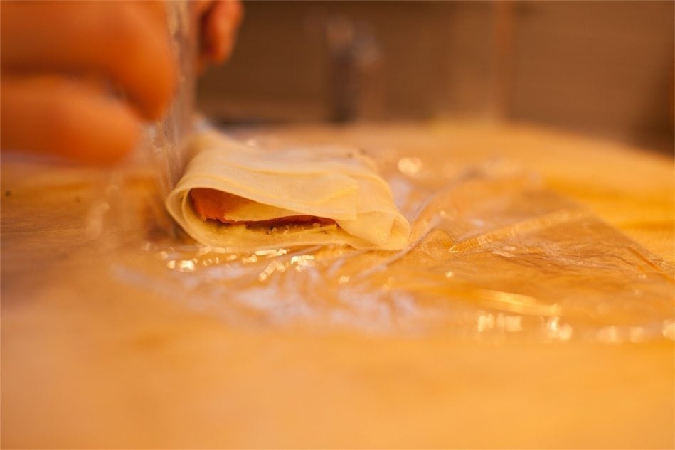 By folding the plastic wrap over the salmon, it's easy to wrap the potato slices around the salmon.